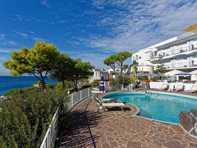 Hotelový bazén s deštníky vedle pobřeží a modré oblohy s mraky