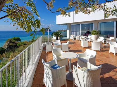 Terrazza con sedie e tavoli bianchi con vista sul mare in una giornata di sole