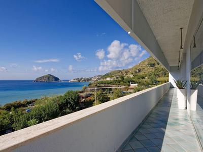 Balkon hotelu s výhledem na moře, modrá obloha a ostrov v pozadí