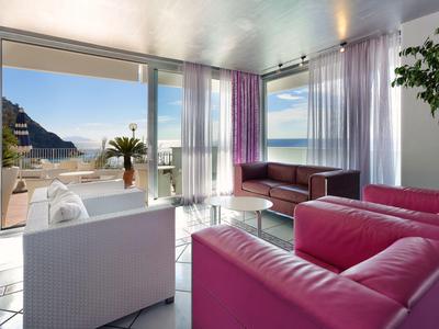 Soggiorno moderno con grandi finestre e vista sul mare e sulle montagne.