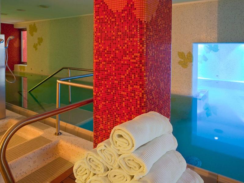 Interiér moderního wellness s vířivkou, ručníky a ambientním osvětlením.