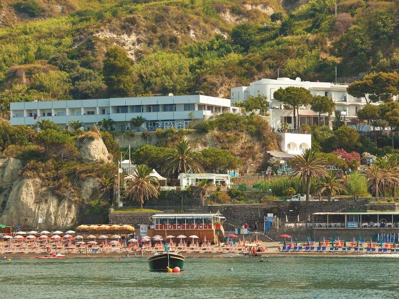 Hotelový komplex na svahu s pláží a lehátky u vody