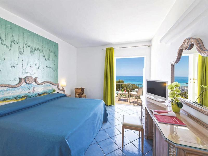 Světlý hotelový pokoj s výhledem na moře a modrou dlažbou