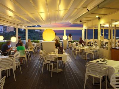 Zadaszony taras restauracyjny o zachodzie słońca z gośćmi i ciepłym oświetleniem.