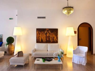 Helles Wohnzimmer mit weißen Möbeln, zwei Stehlampen und einem Gemälde an der Wand.