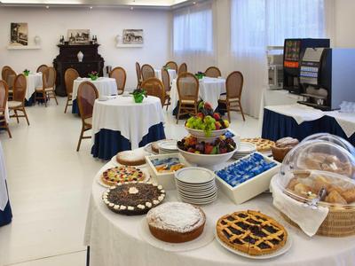 Pokój kawowy z nakrytymi stołami, ciastami, wypiekami i miską z owocami.