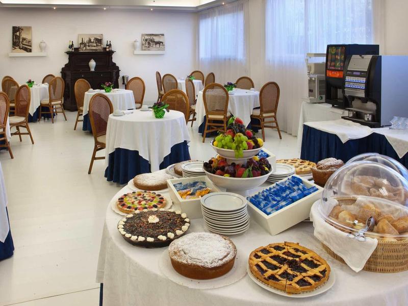 Pokój kawowy z nakrytymi stołami, ciastami, wypiekami i miską z owocami.