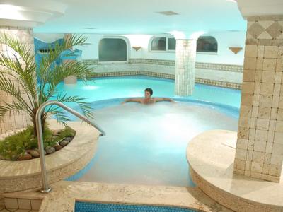 Piscina coperta con acqua calda, circondata da colonne e atmosfera rilassante.