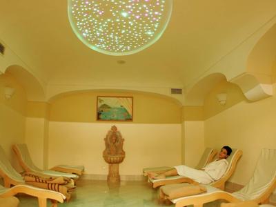 Sala relax con lettini, luce calda e lampada decorativa sul soffitto in ambiente luminoso.