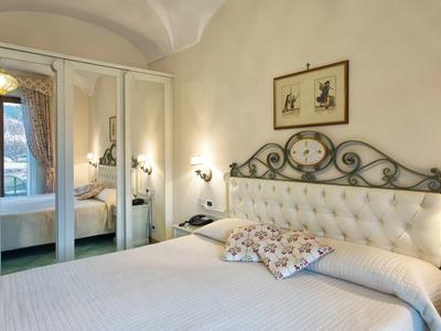 Przytulna sypialnia z łóżkiem podwójnym, szafą z lustrami i dekoracyjnymi obrazami na ścianie.