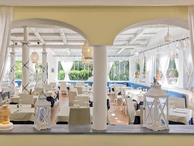 Jasna restauracja z białymi kolumnami, wygodnymi krzesłami i morską dekoracją wewnątrz.