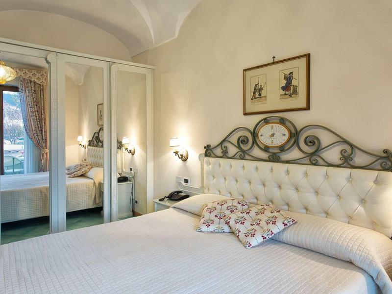 Camera luminosa con letto grande, testiera decorativa e ante dell'armadio a specchio.