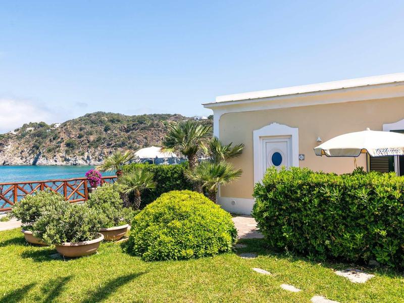 Giardino verde con cespugli e terrazza di una casa vicino al mare e alle scogliere.