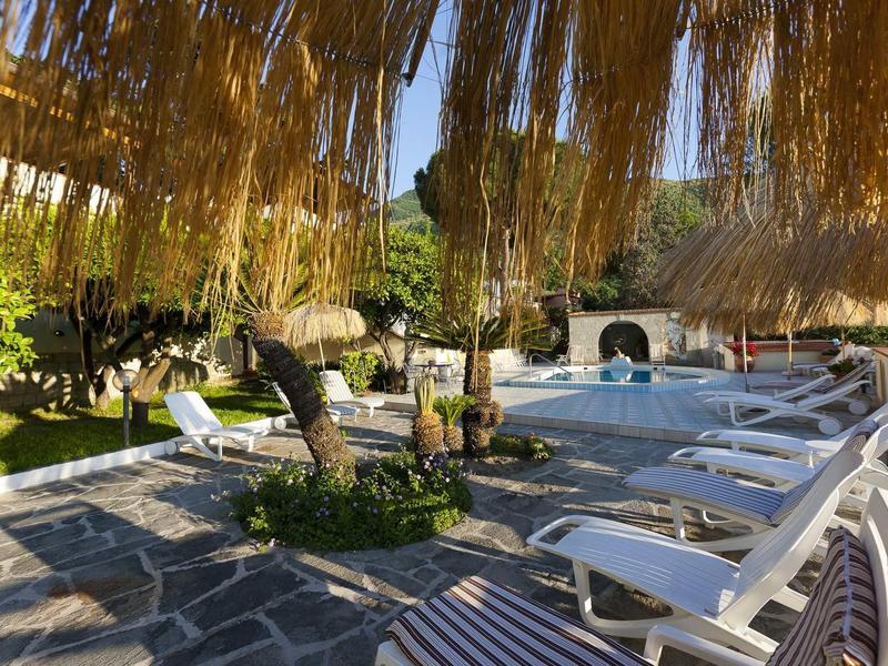 Garten mit gemütlichen Liegestühlen, Pool, Palmen und schattenspendenden Strohdächern.