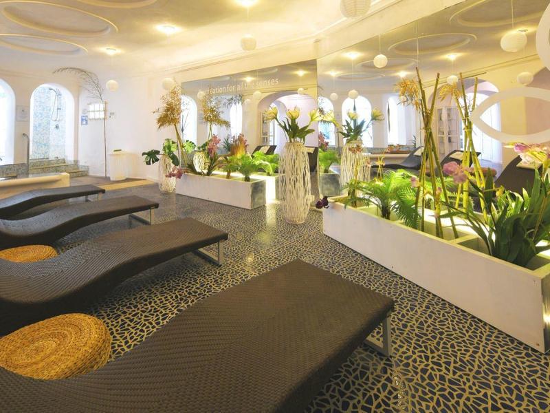 Moderní hotelová lobby s lehátky, rostlinami a teplou světelnou atmosférou.