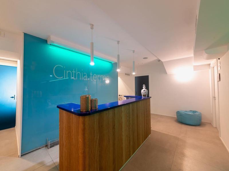 Reception di un hotel moderno con bancone in legno e illuminazione blu.