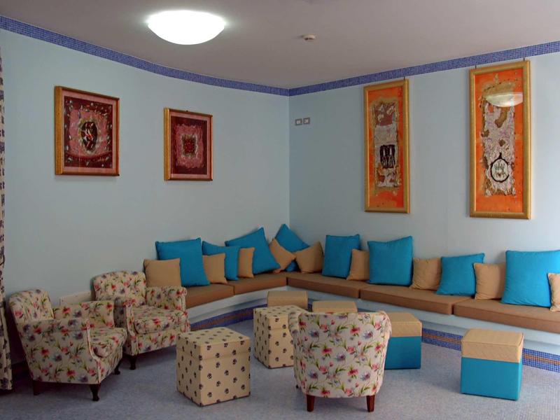 Knusse hotel lounge met blauwe kussens en gemêleerde fauteuils.