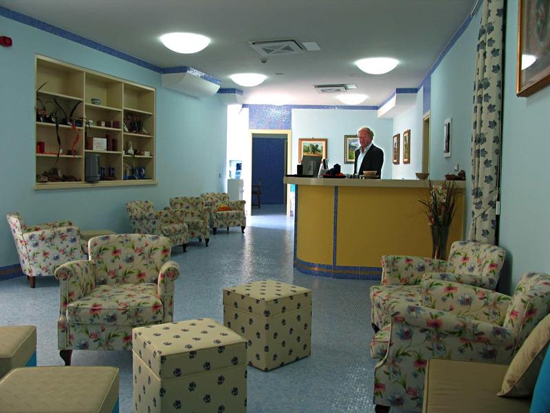 Lichte hotel lobby met receptiebalie en gezellige bloemen fauteuils.