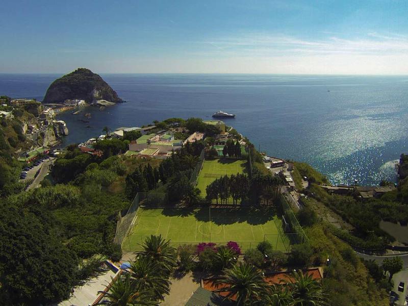 Uitzicht op een kustlandschap met groen park, gebouwen en zee op de achtergrond.