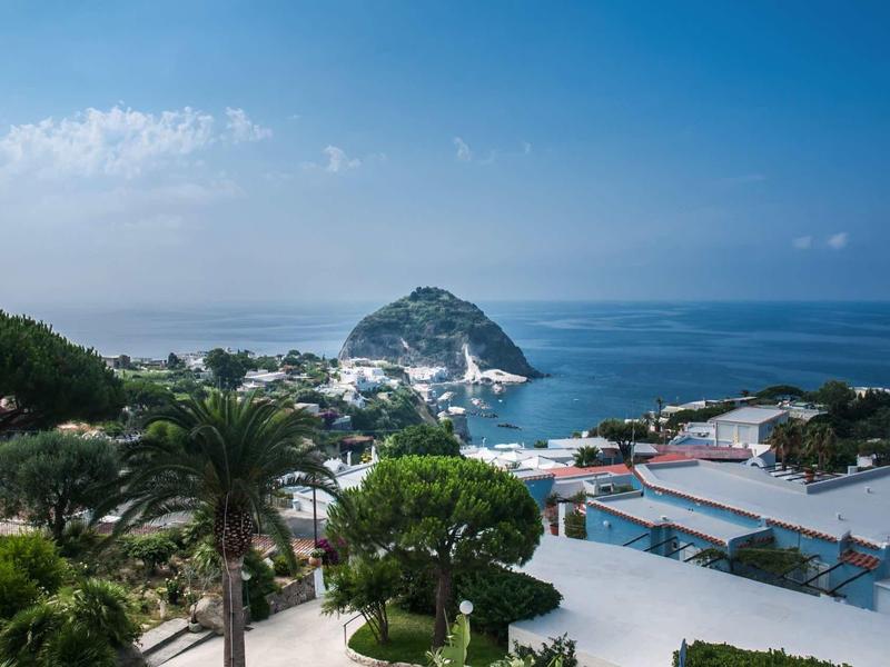 Uitzicht op een kustplaats met een opvallende heuvel en de zee op de achtergrond bij heldere lucht.