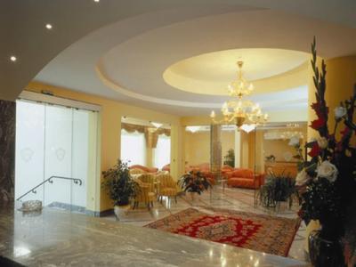 Elegante Hotellobby mit Kronleuchter, Teppich und Sitzbereich in warmen Farben.