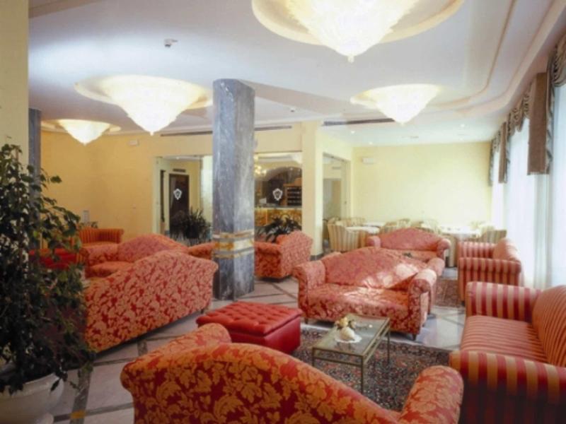 Großes Wohnzimmer mit mehreren roten gemusterten Sofas, Glastisch und moderner Deckenbeleuchtung.