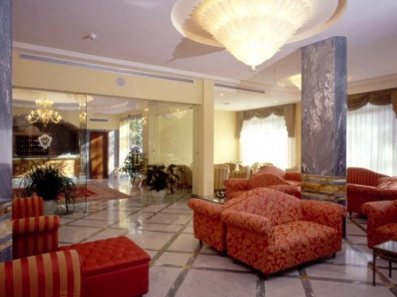 Elegantes Wohnzimmer mit bequemen roten Sofas, großem Kronleuchter und Marmorboden.