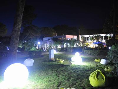 Beleuchteter Garten mit beleuchteten Kugeln und Sitzsäcken bei Nacht im Außenbereich eines Hotels.