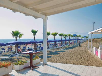 Spiaggia con ombrelloni blu, lettini e area coperta con tavoli