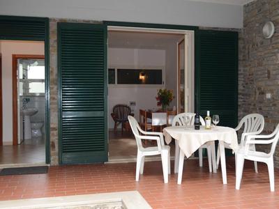 Terrasse mit weißem Gartentisch und Stühlen vor großer Glas-Schiebetür