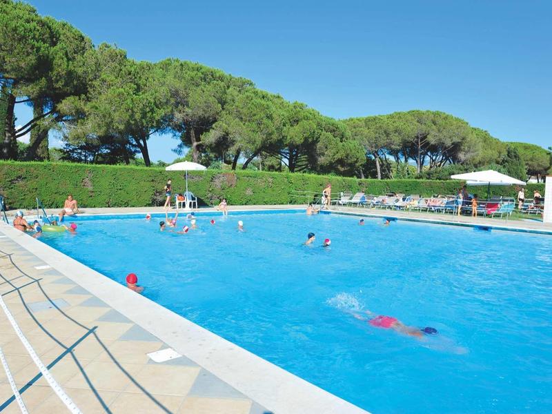 Piscina per il tempo libero con diverse persone, molto verde e cielo limpido