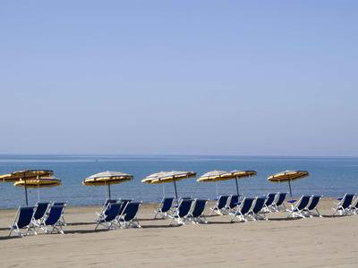 Chaises de plage vides avec parasols sur une plage calme sous un ciel bleu clair.