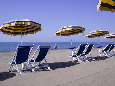 Ciel bleu, parasols jaunes et noirs et chaises longues bleues sur une plage de sable au bord de la mer