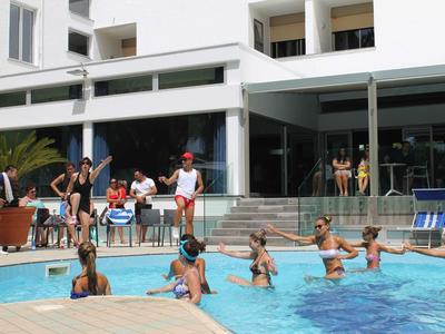 Des personnes apprennent à nager dans une piscine d'hôtel par une journée ensoleillée.