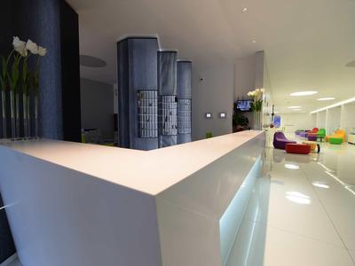 Réception d'hôtel moderne blanche avec lignes épurées et sol lumineux.