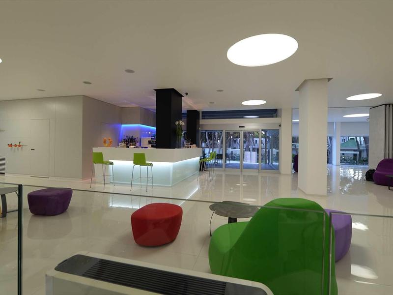 Hall d'hôtel moderne avec sièges colorés et réception dans un espace lumineux et ouvert.