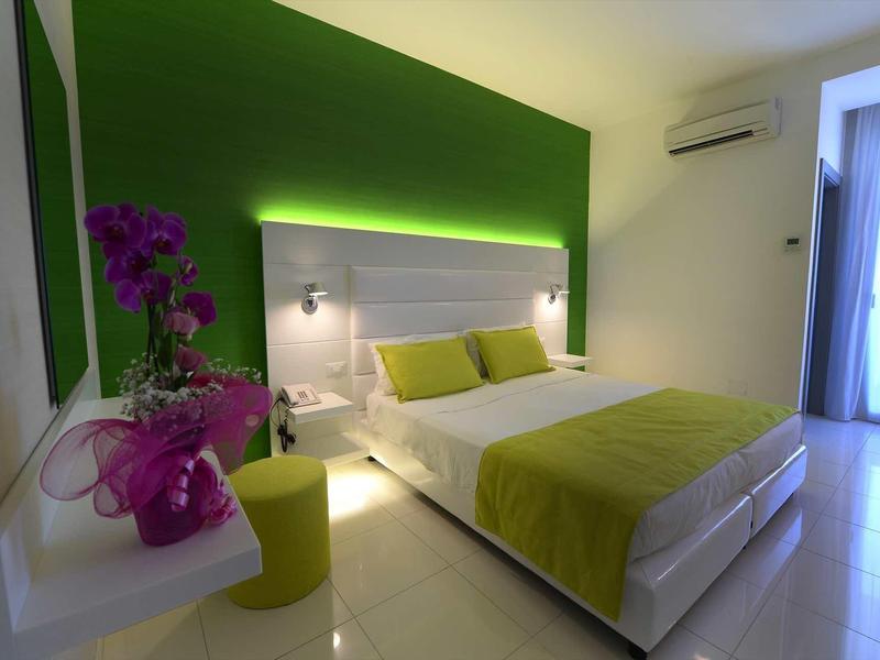Chambre d'hôtel moderne avec accents verts, lit double et éclairage élégant.