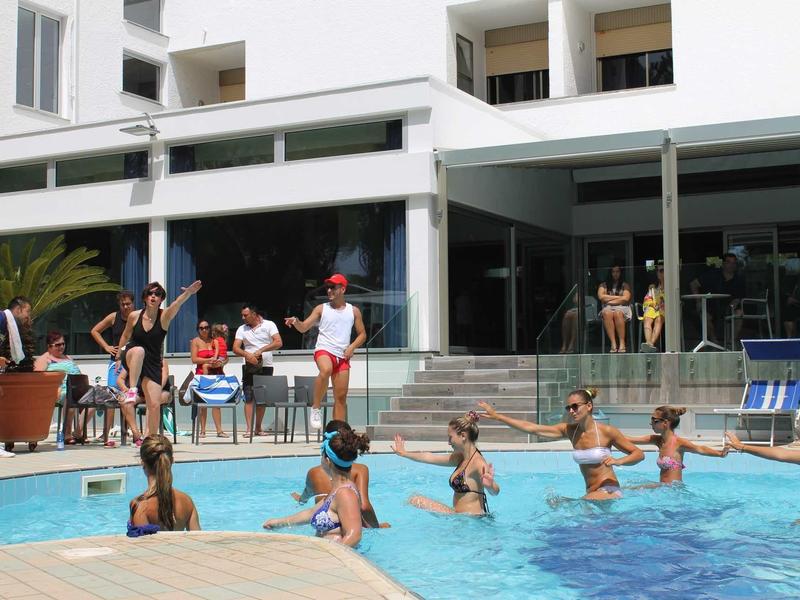 Des personnes apprennent à nager dans une piscine d'hôtel par une journée ensoleillée.