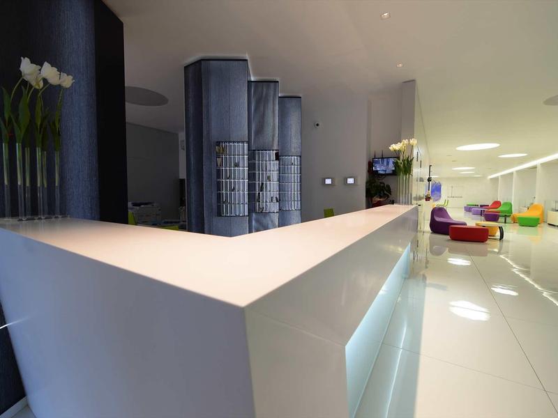 Réception d'hôtel moderne blanche avec lignes épurées et sol lumineux.