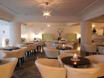 Elegantní hotelová lounge s kulatými stolky, pohodlnými křesly a tlumeným osvětlením.