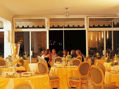 Elegantní restaurace se prostřenými stoly a hosty v teple osvětlené místnosti.