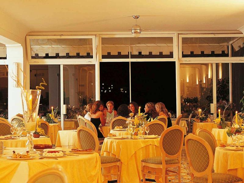 Elegantní restaurace se prostřenými stoly a hosty v teple osvětlené místnosti.