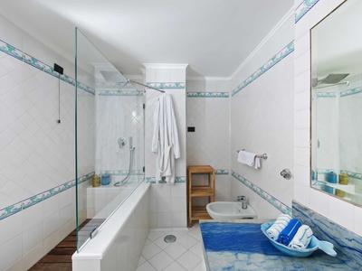 Salle de bains moderne avec baignoire, bidet, serviette bleue et grands miroirs.
