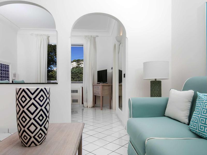 Espace de vie moderne et lumineux avec canapé bleu, coussin à motifs et objet décoratif sur table en bois.