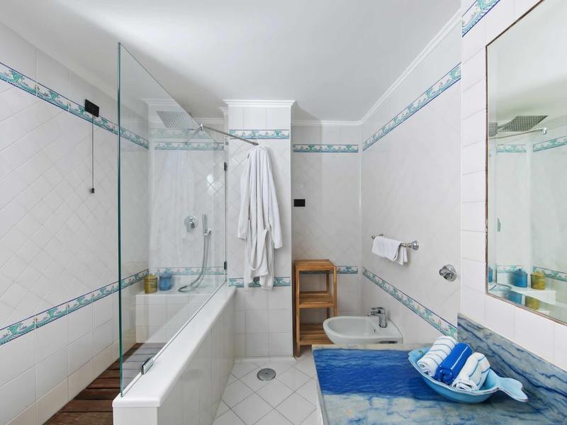 Salle de bains moderne avec baignoire, bidet, serviette bleue et grands miroirs.