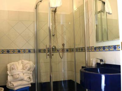 Modern bathroom with curved shower, blue sink, and towels on a blue stool.