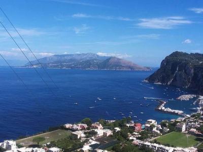 View of a coastal town with blue sea, mountains, and clear sky.