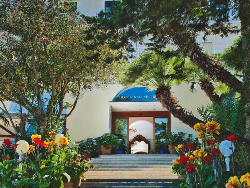 Stairway to a hotel entrance with blooming flowers and trees around.