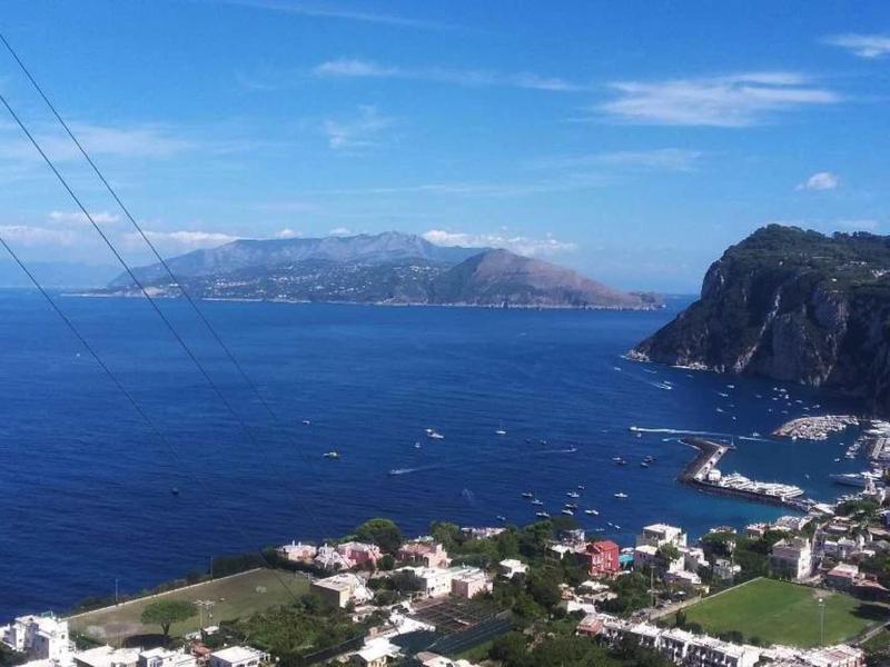 View of a coastal town with blue sea, mountains, and clear sky.
