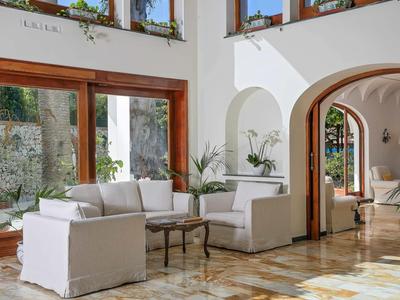 Lichte hotellounge met witte banken, glazen deuren en marmeren vloer.